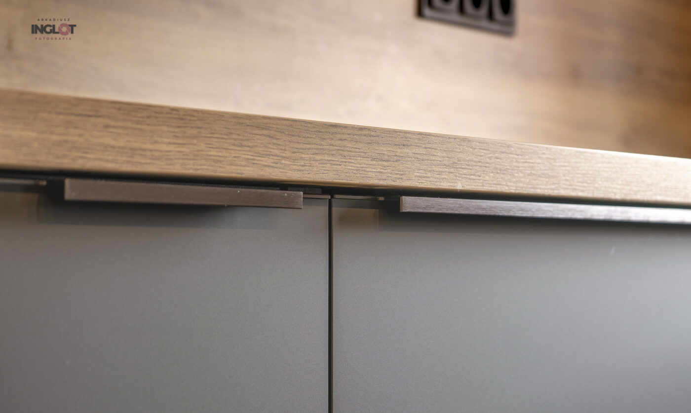 Zbliżenie na czarne fronty kuchenne z metalowymi uchwytami – wyzwania w fotografii wnętrz.