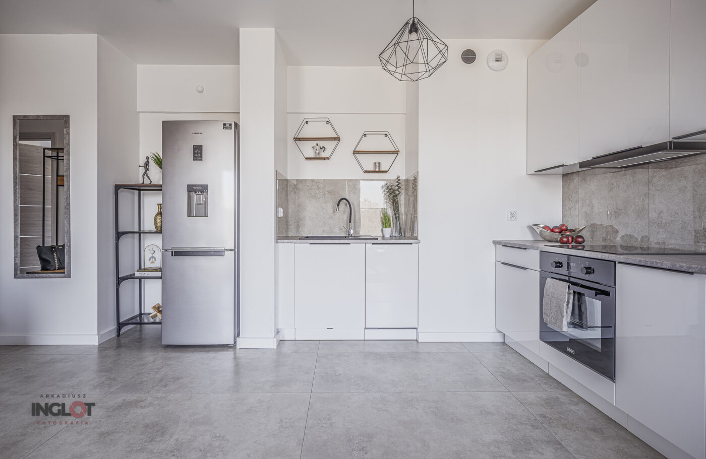 Nowoczesny aneks kuchenny otwarty na przestronny salon, jasna kolorystyka, eleganckie wykończenia, funkcjonalny układ i naturalne oświetlenie.