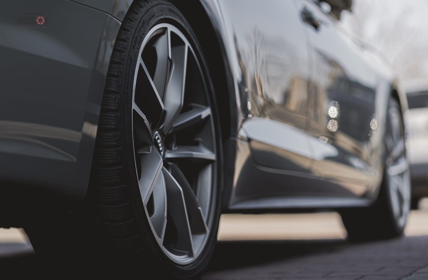 Boczny widok od spodu samochodu Audi z ujęciem dwóch felg, podkreślający sportowy styl, eleganckie linie i precyzję wykonania.