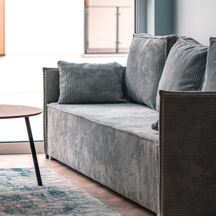 otografia wnętrz – sofa, niebieskoszary dywan i stolik kawowy na tle nowoczesnych mebli kuchennych