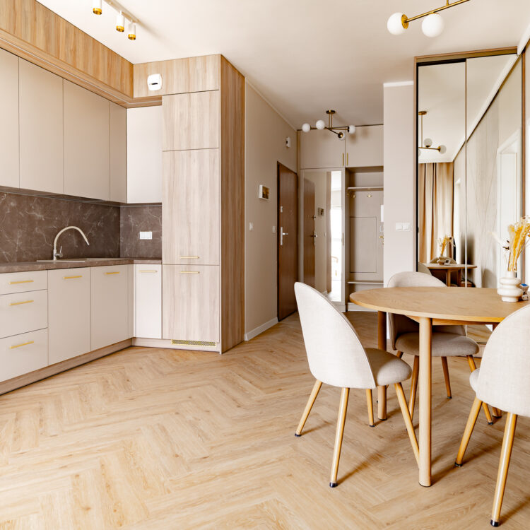 Kuchnia połączona z jadalnią w nowoczesnym stylu z drewnianym stołem i jasnymi meblami.