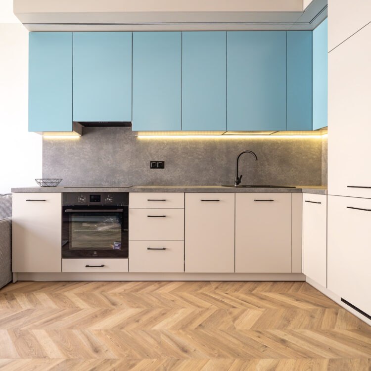 Widok na aneks kuchenny w pastelowych niebieskich kolorach, z nowoczesnymi meblami i eleganckim wykończeniem.