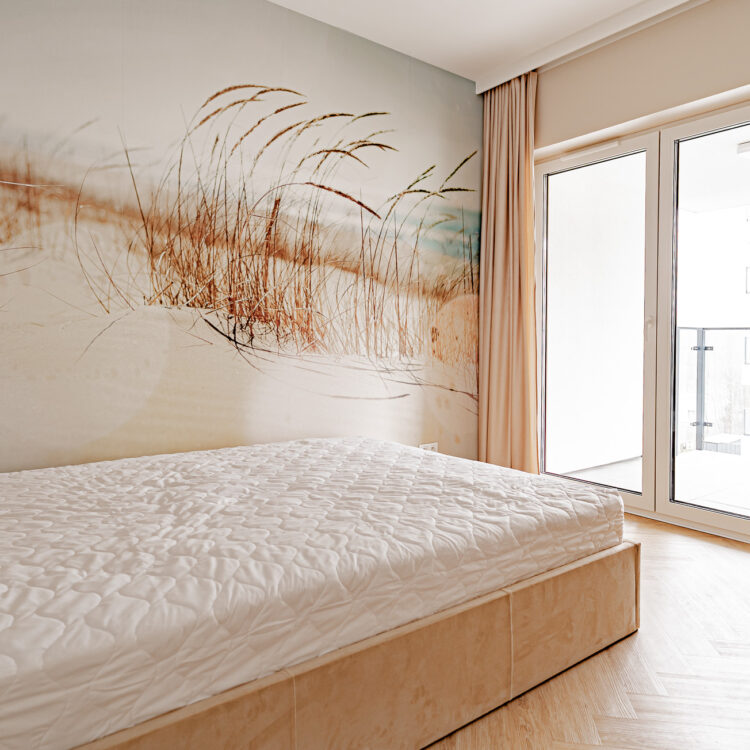 Sypialnia z dużym łóżkiem i wyjściem na balkon w stylu boho.