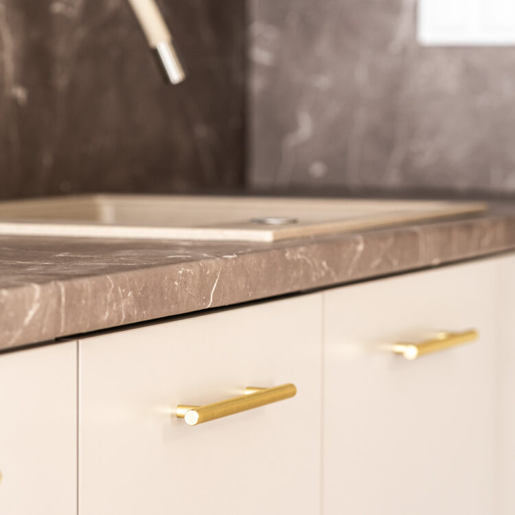 Zbliżenie na złote uchwyty i jasne fronty kuchenne w stylu boho.