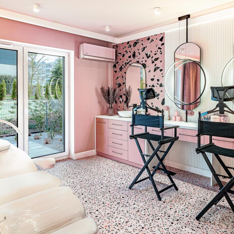 Stanowiska kosmetyczne i fotel do makijażu w różowym wnętrzu.